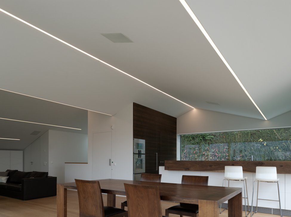 Interno open space con cucina moderna e illuminazione lineare