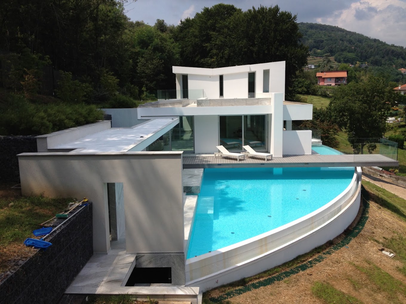 Villa contemporanea con piscina curva a sfioro e grandi vetrate
